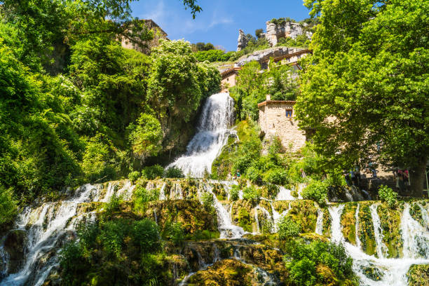 Water cascade between trees in sunny day, Orbaneja del Castillo, Spain